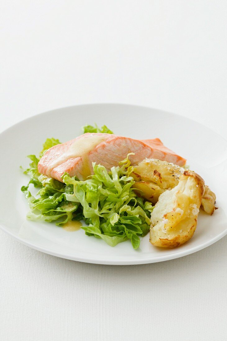Poached salmon fillet with mustard sauce on a bed of salad