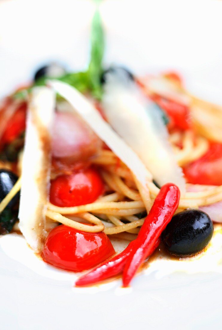 Spaghetti with tomatoes, olives, chilli and parmesan (close-up)