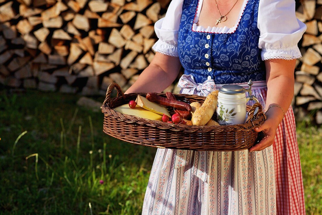 A woman wearing a dirndl and carrying a tray holding a light meal