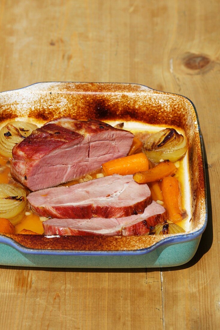 Roast ham with vegetables in the roasting tin