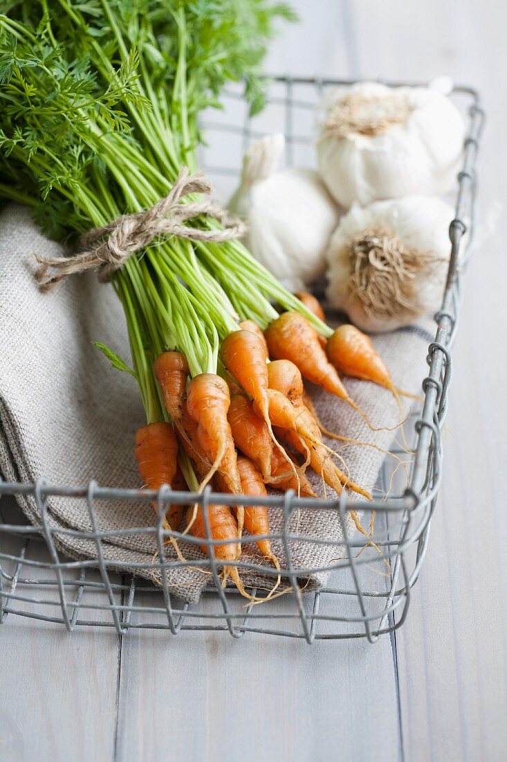 A bunch of baby carrots and garlic in a basket