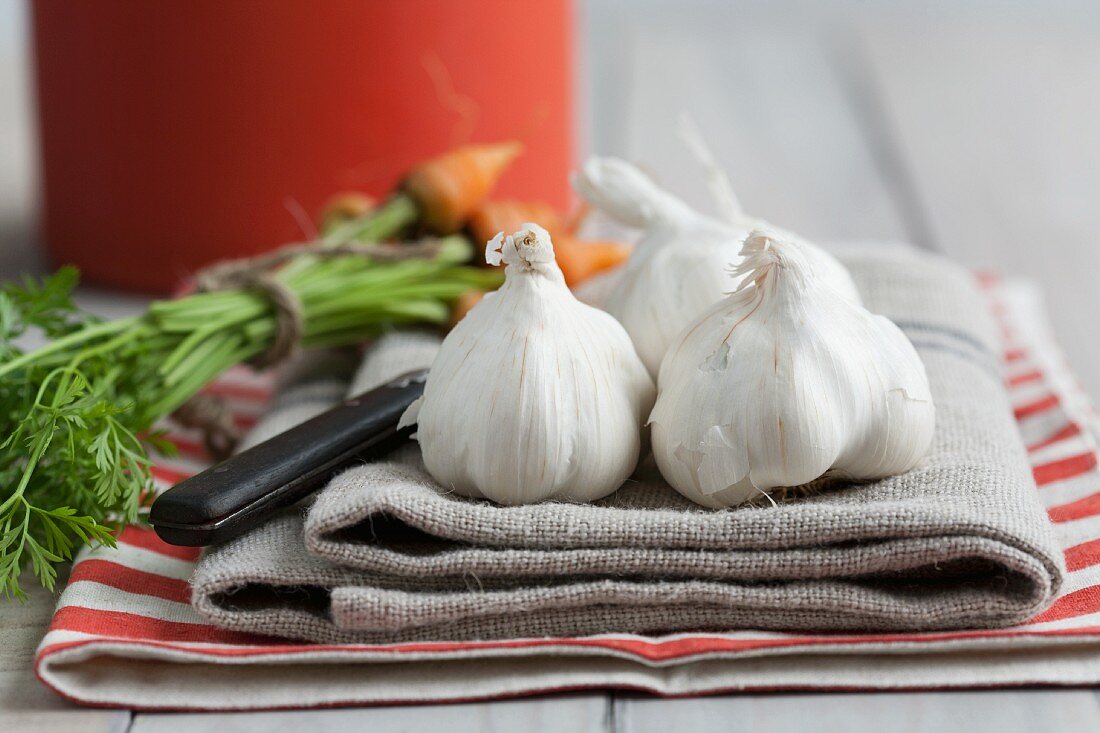 Garlic bulbs and baby carrots on a tea towel