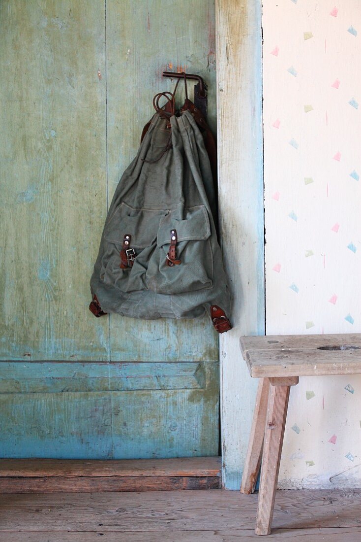 Rustic duffel bag hanging from handle of old country-house door