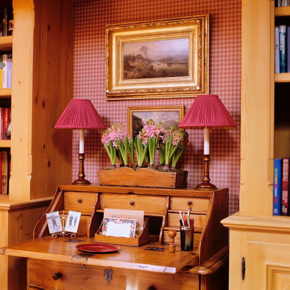 Romantic niche with red houndstooth wallpaper and table lamps on antique bureau