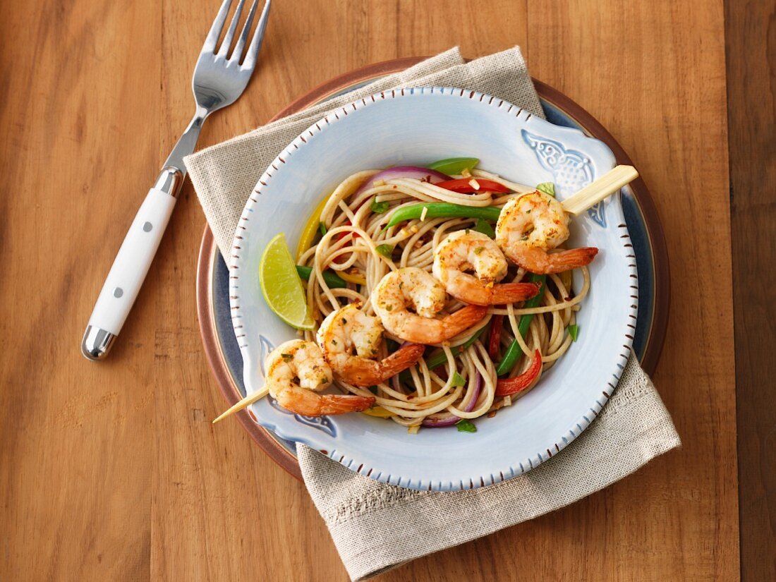Spaghetti with vegetables and a prawn skewer