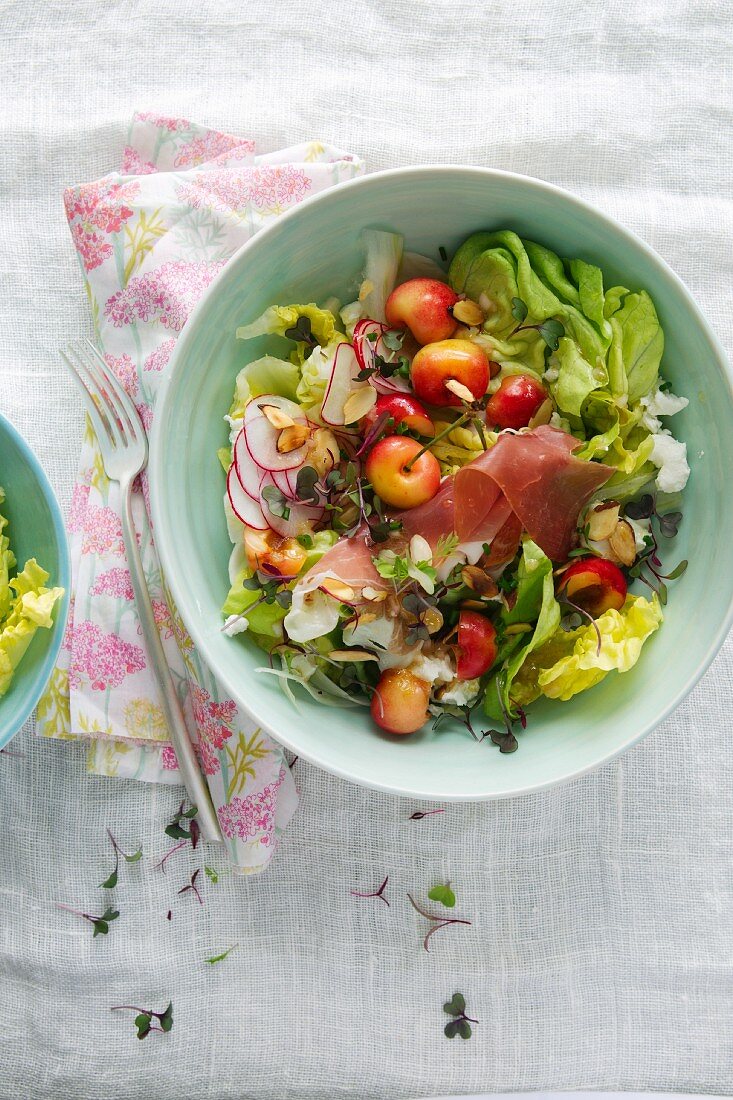 Gemischter grüner Salat mit frischen Kirschen, Radieschen und Prosciutto