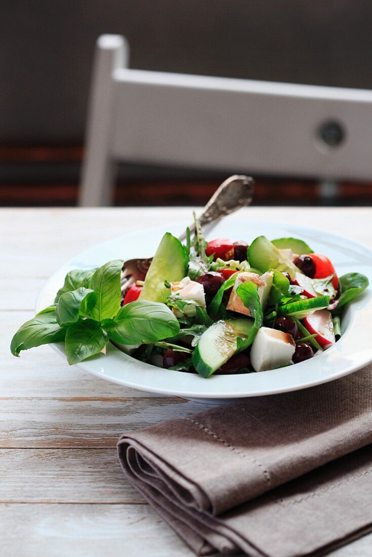 Greek salad with basil, cucumber, tomato, olives and radish