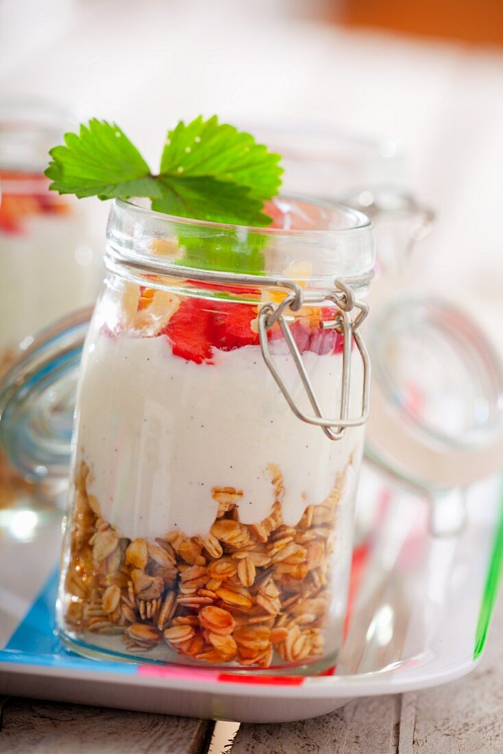 Zutaten für Müsli in einem Glas: Haferflocken, Vanillejoghurt und Erdbeeren