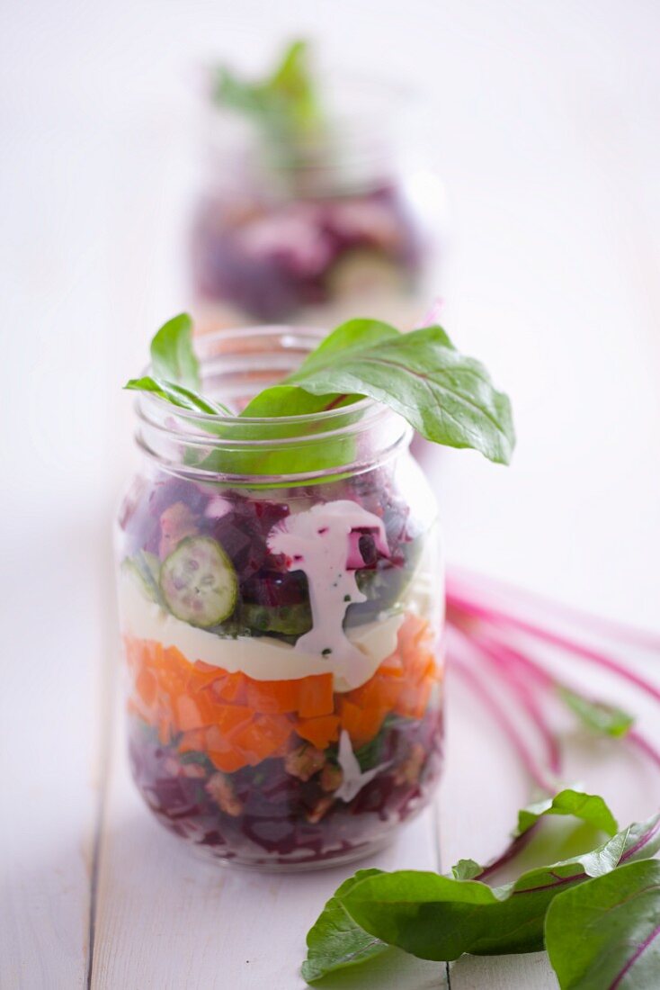 Salad ingredients layered in a jar (beetroot, carrot, mayonnaise, cucumber and chard)