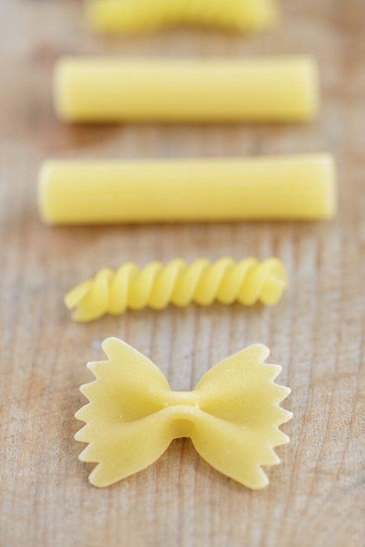 Various types of pasta on a wooden surface