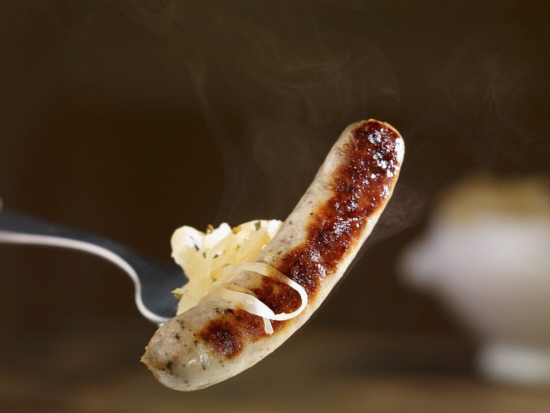 A steaming grilled bratwurst sausage with sauerkraut