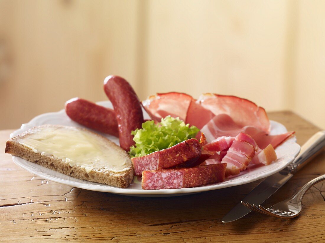 A cold meat platter with a slice of buttered bread