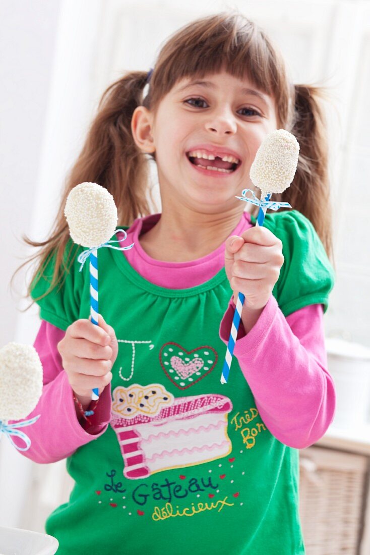 A girl holding two egg-shaped cake pops