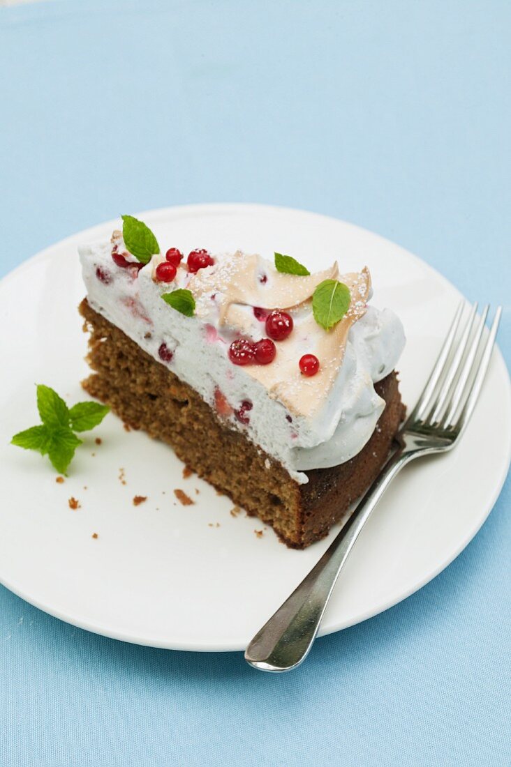 Ein Stück Johannisbeerkuchen mit Baiserhaue und Minze