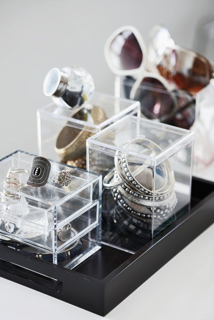 Kleine Acrylglasboxen zur Aufbewahrung von Schmuck und Brillen auf schwarzem Tablett