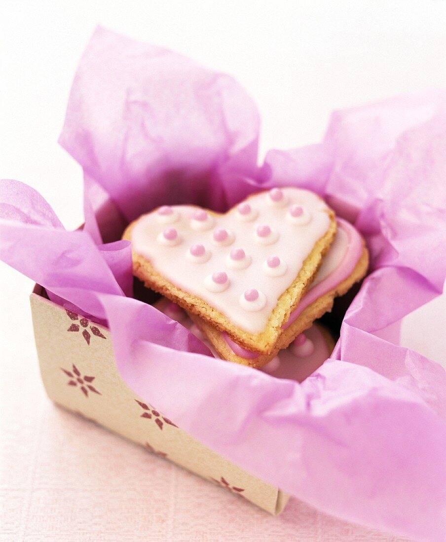 Herzförmige Plätzchen in einer Schachtel mit rosa Papier