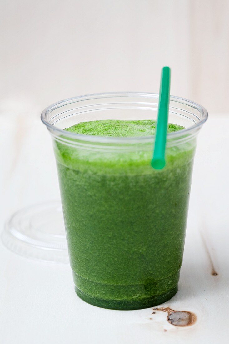 A green smoothie made with spinach, lamb's lettuce, apple, banana and apple mint in a plastic cup