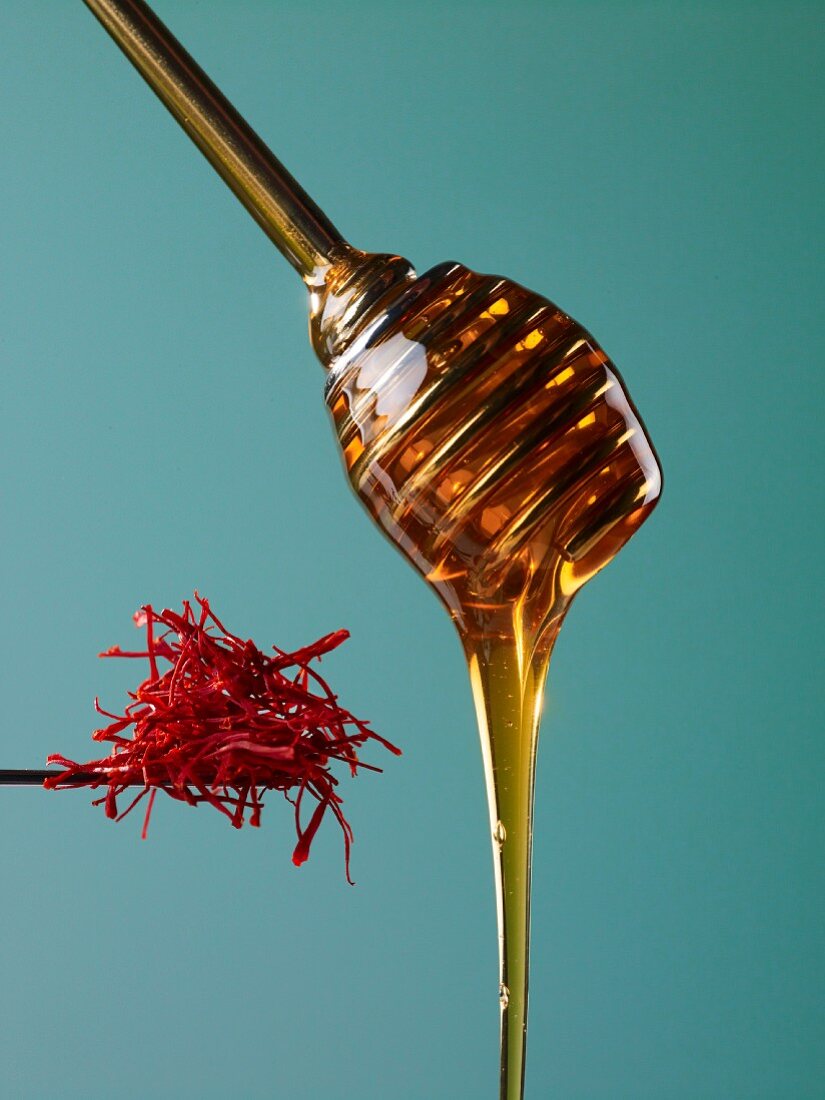 Honey flowing from a honey dipper, and saffron threads