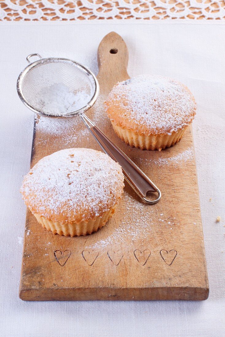 Vanillemuffins mit Puderzucker auf Holzbrett