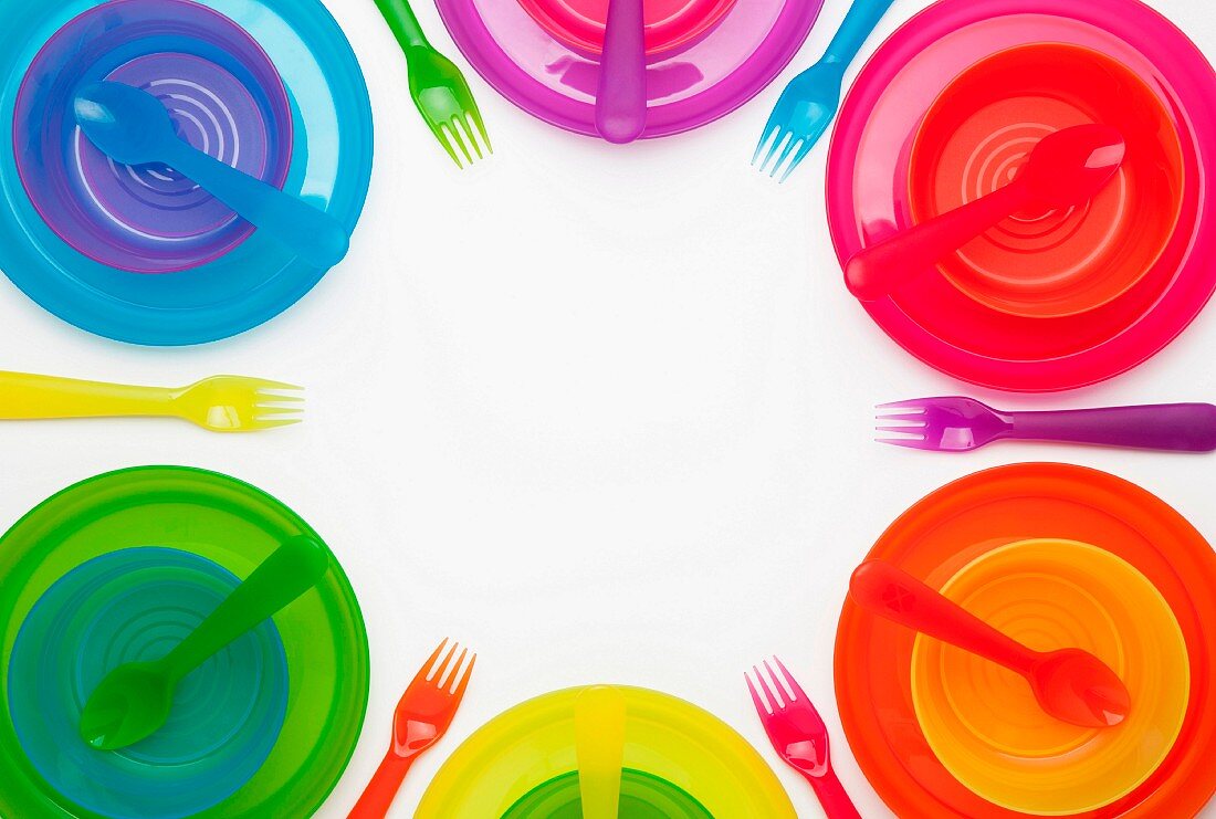 Colourful plastic plates, cups, bowls, spoons and forks