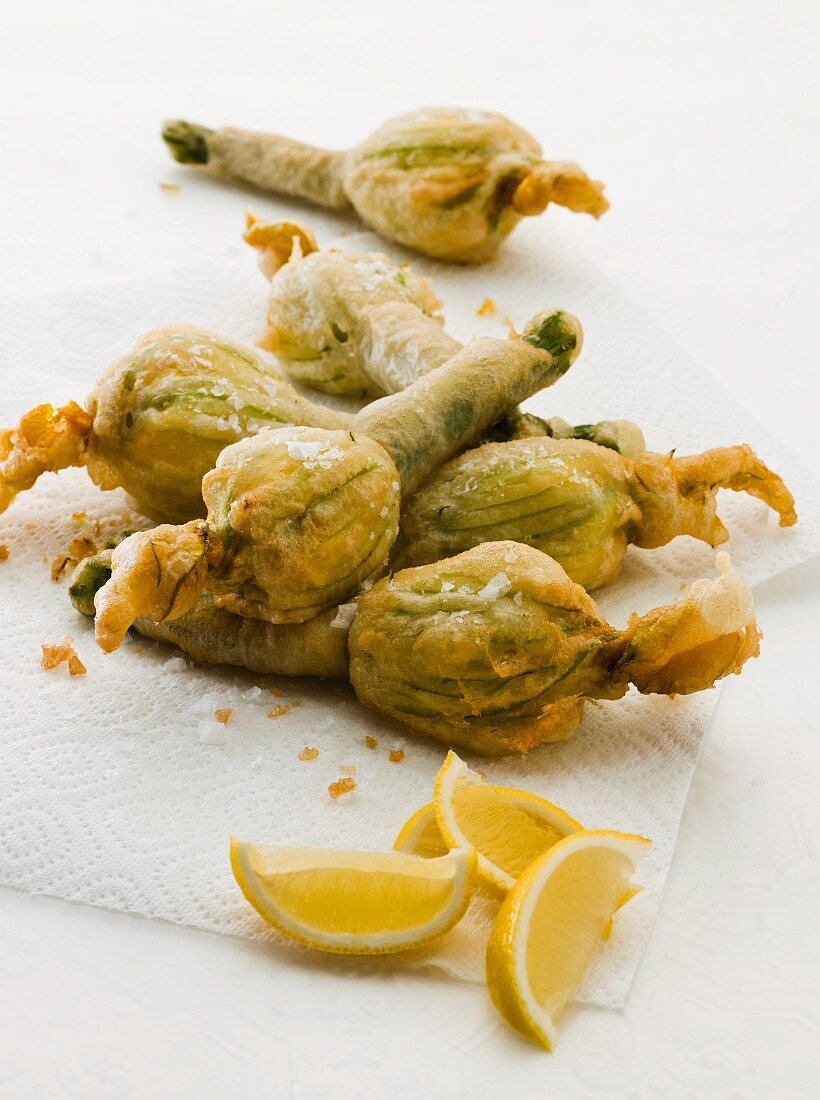 Deep-fried courgette flowers with lemon wedges