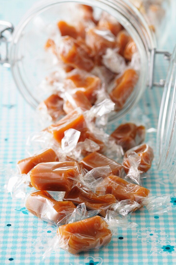 Individually wrapped toffees spilling out of a glass container