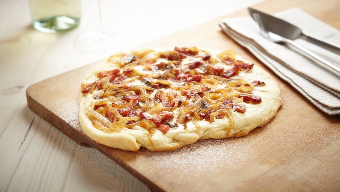 Tarte flambée topped with bacon and onions