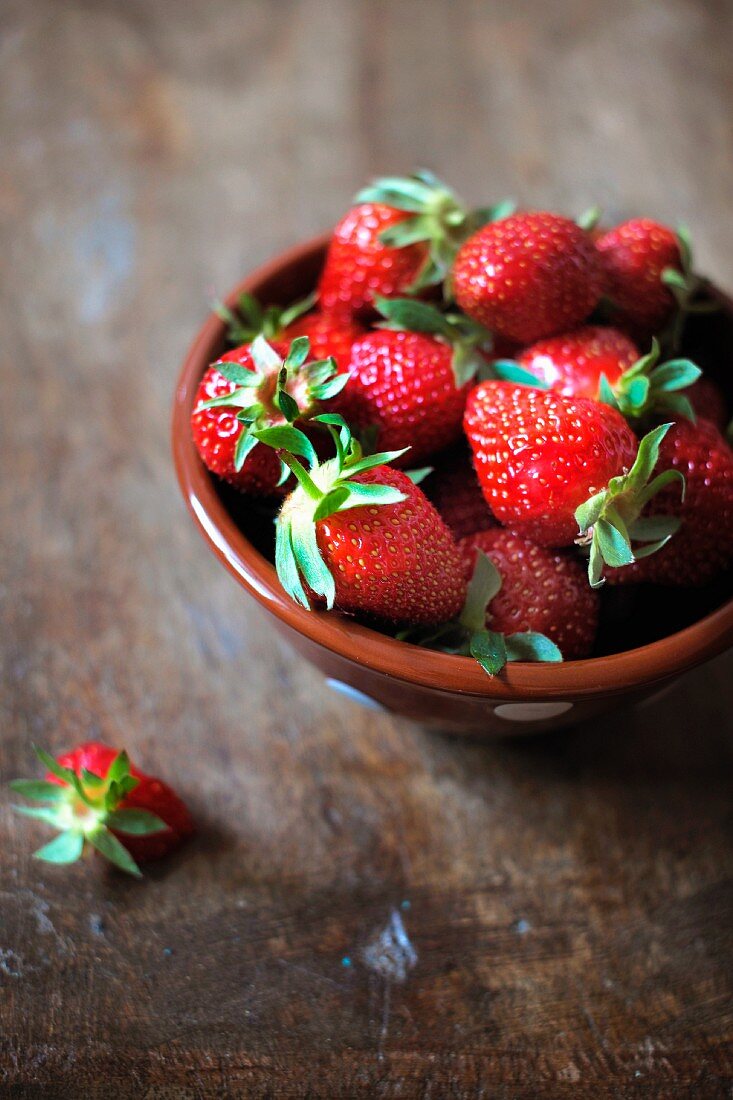 Frische Erdbeeren; daneben eine angebissene Erdbeere