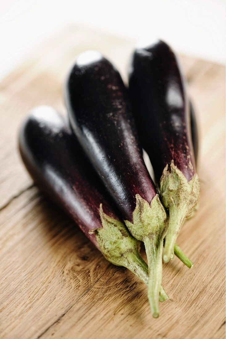 Several aubergines on a wooden board