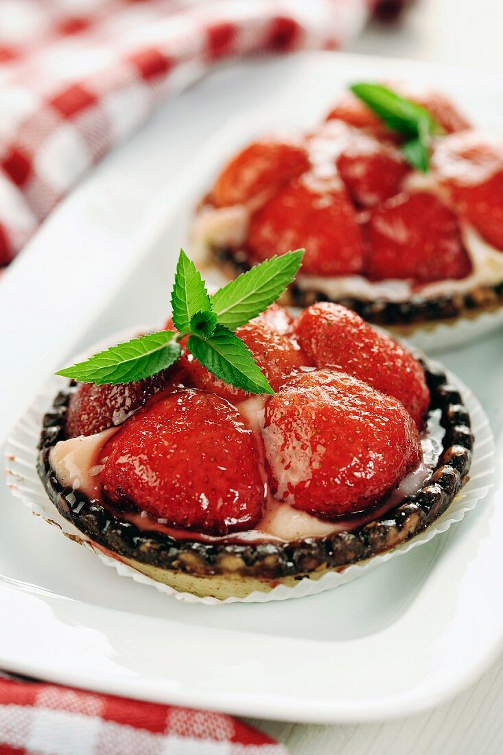 Individual strawberry tarts with mint leaves