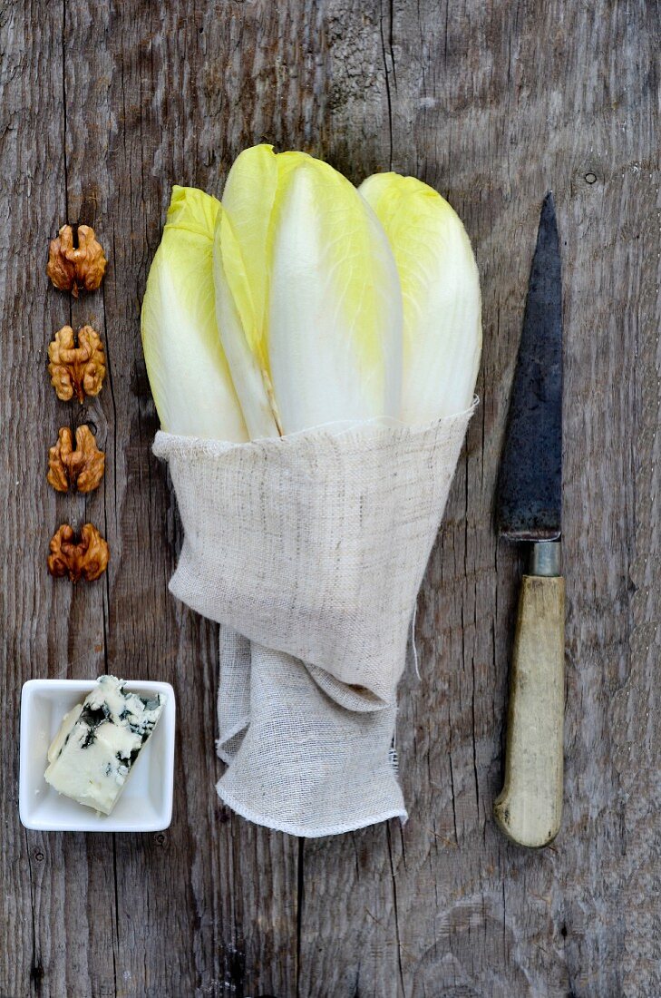 Zutaten für Salat: Chicorée, Roquefort und Walnüssse auf Holzuntergrund