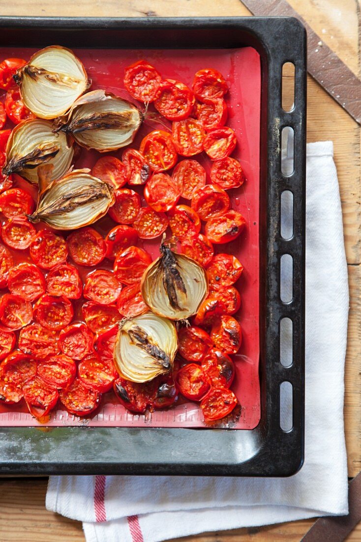 Roasted cherry tomatoes and onions in a baking tray