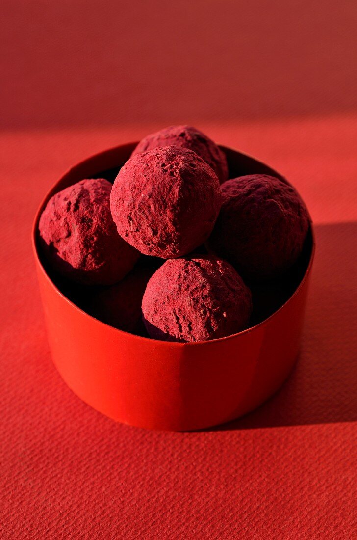 Several blackcurrant truffles in a red box
