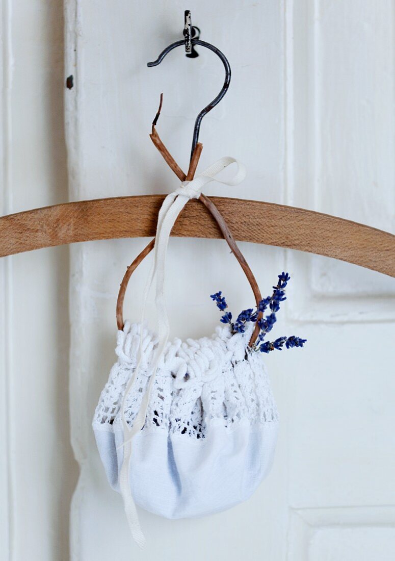 Coat hanger with lavender flowers in white, crocheted bag hanging from key in old door
