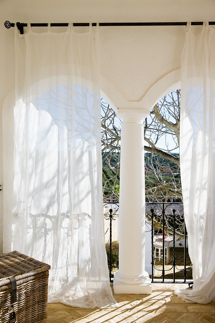 White curtains in front of masonry archways of loggia