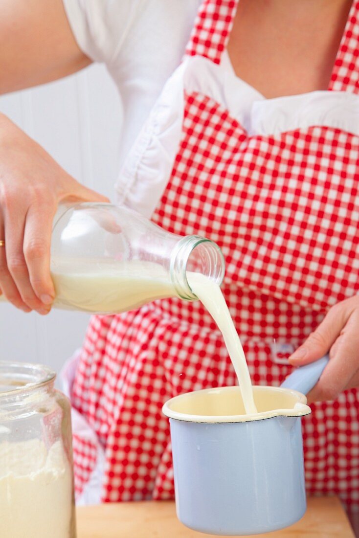 A woman pouring milk into a pan