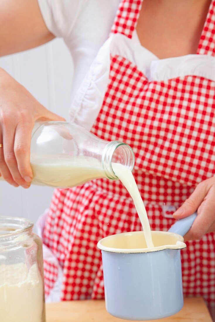 Frau gießt Milch in einen Topf