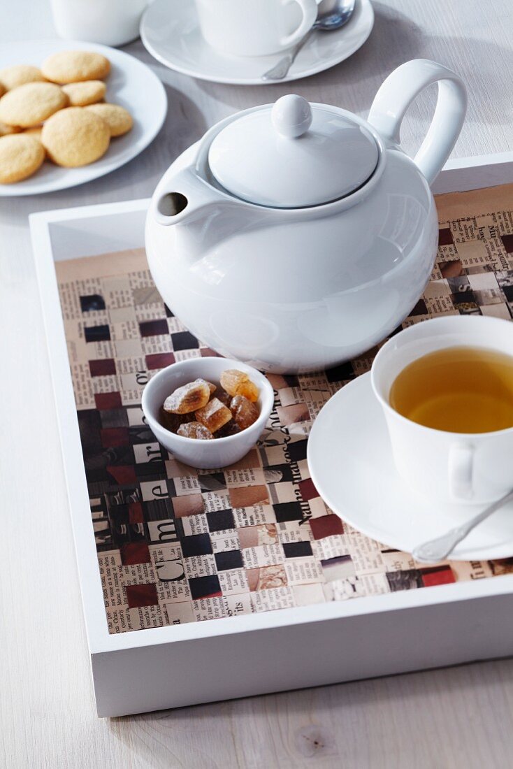 Teapot on woven newspaper table mat on tray