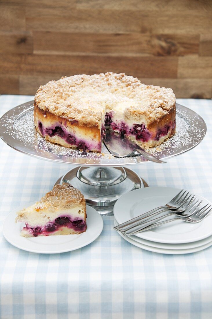 Crumble-topped quark cake with blackberries, one slice cut