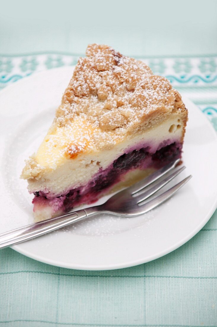 Ein Stück Quark-Streuselkuchen mit Brombeeren