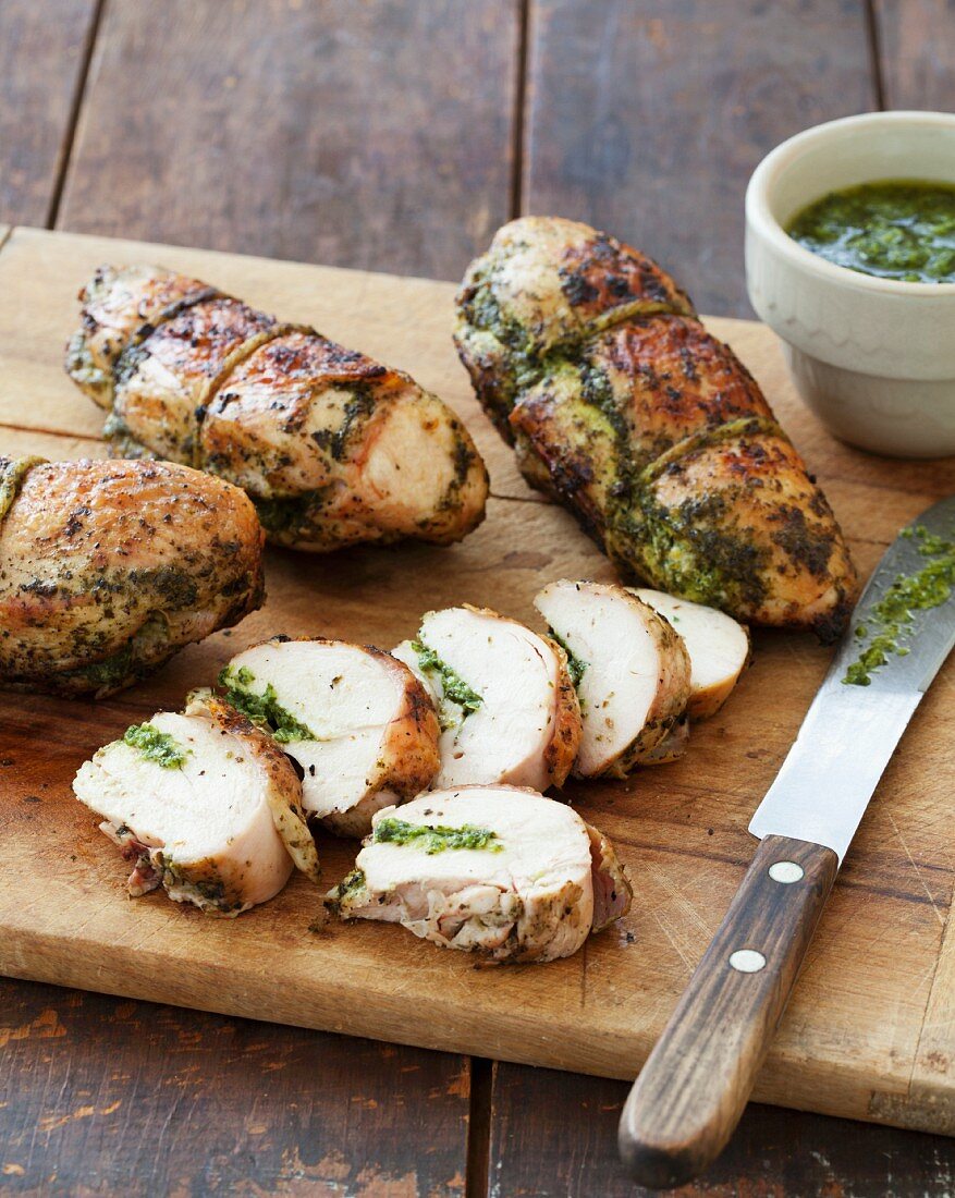 Grilled Pesto Chicken Breasts on a Cutting Board; One Sliced