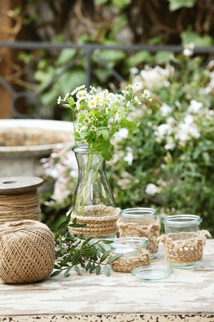 Hand-knitted covers for glass vases & tealight holders on garden table