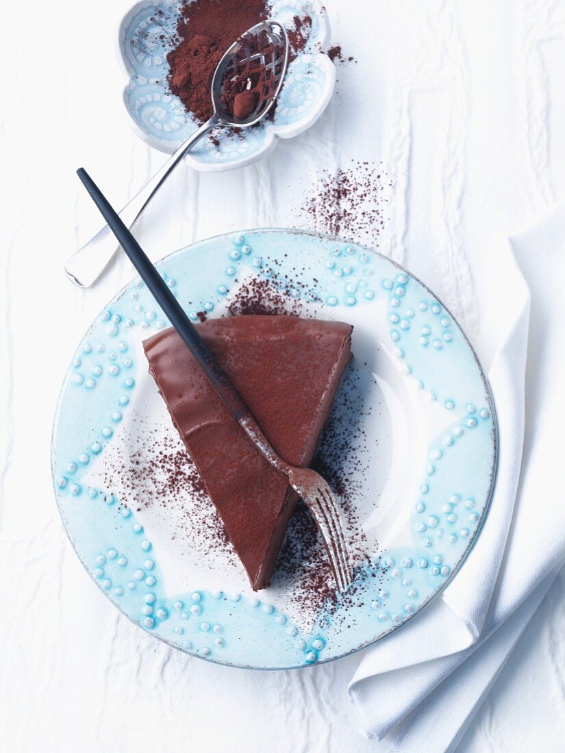 A slice of chocolate cake with cocoa powder