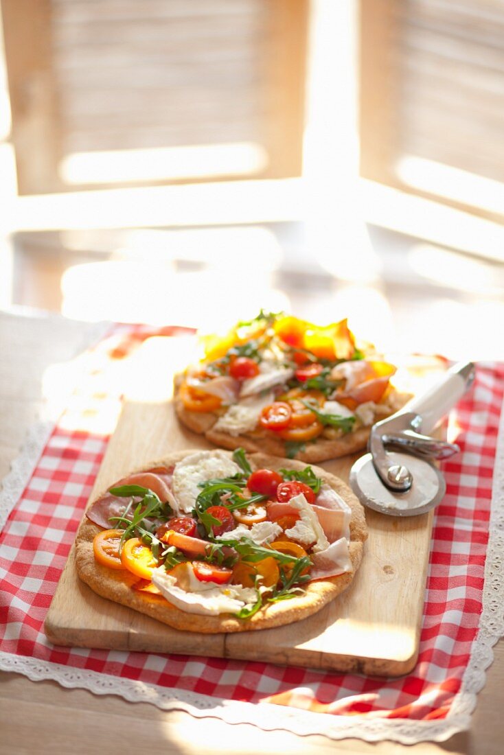 Pizzas mit Rucola, Prosciutto, Ziegenkäse und Tomaten