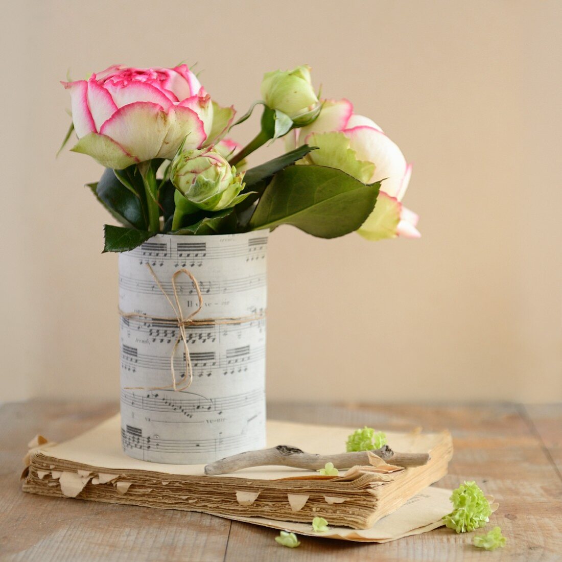 White roses in rolled up sheet music on an old book