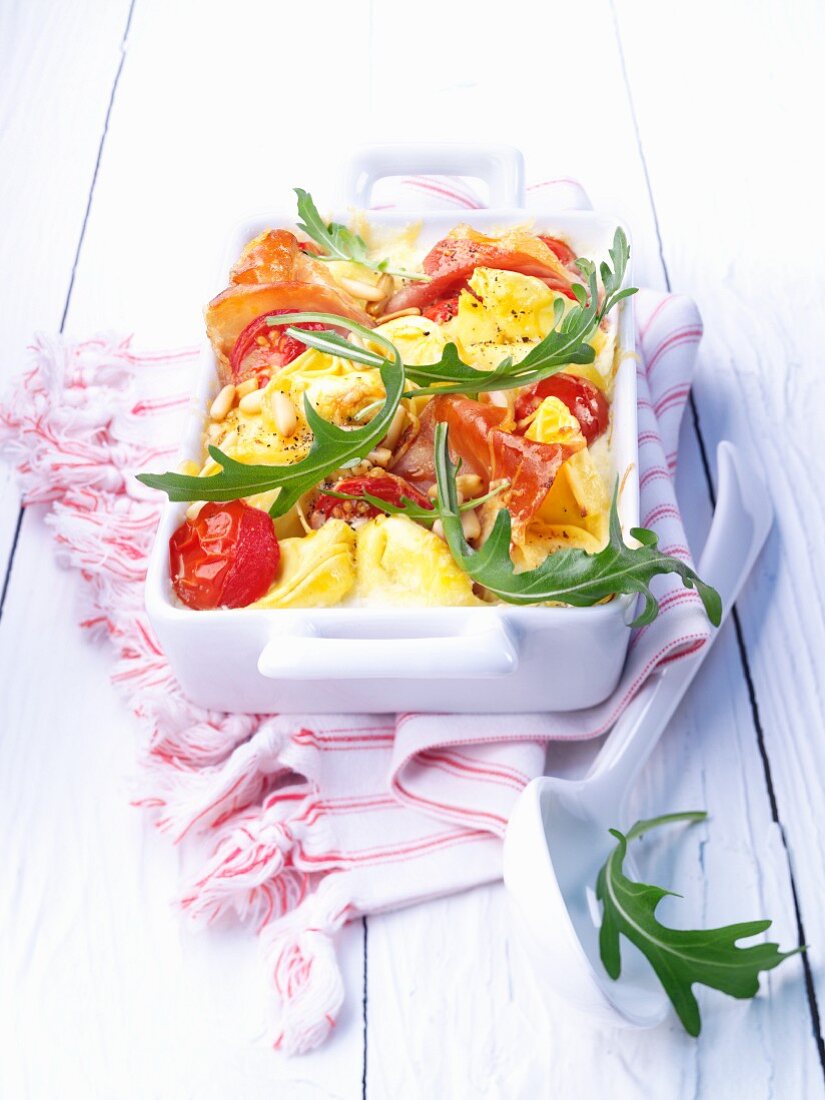 Tortellini casserole with bacon, tomatoes and rocket