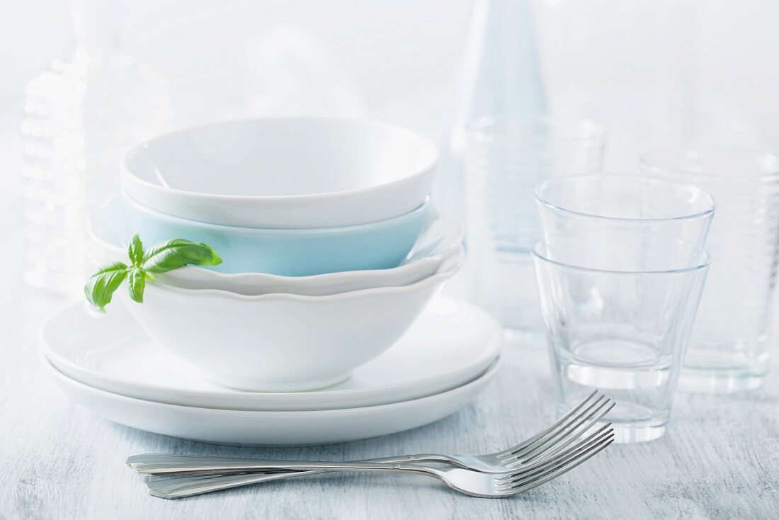 Stacked dinner bowls and plated, drinking glasses and forks