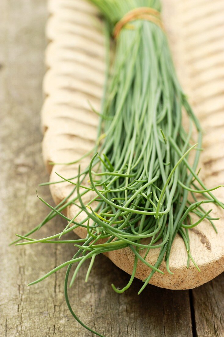 A bunch of chives in a wooden serving dish