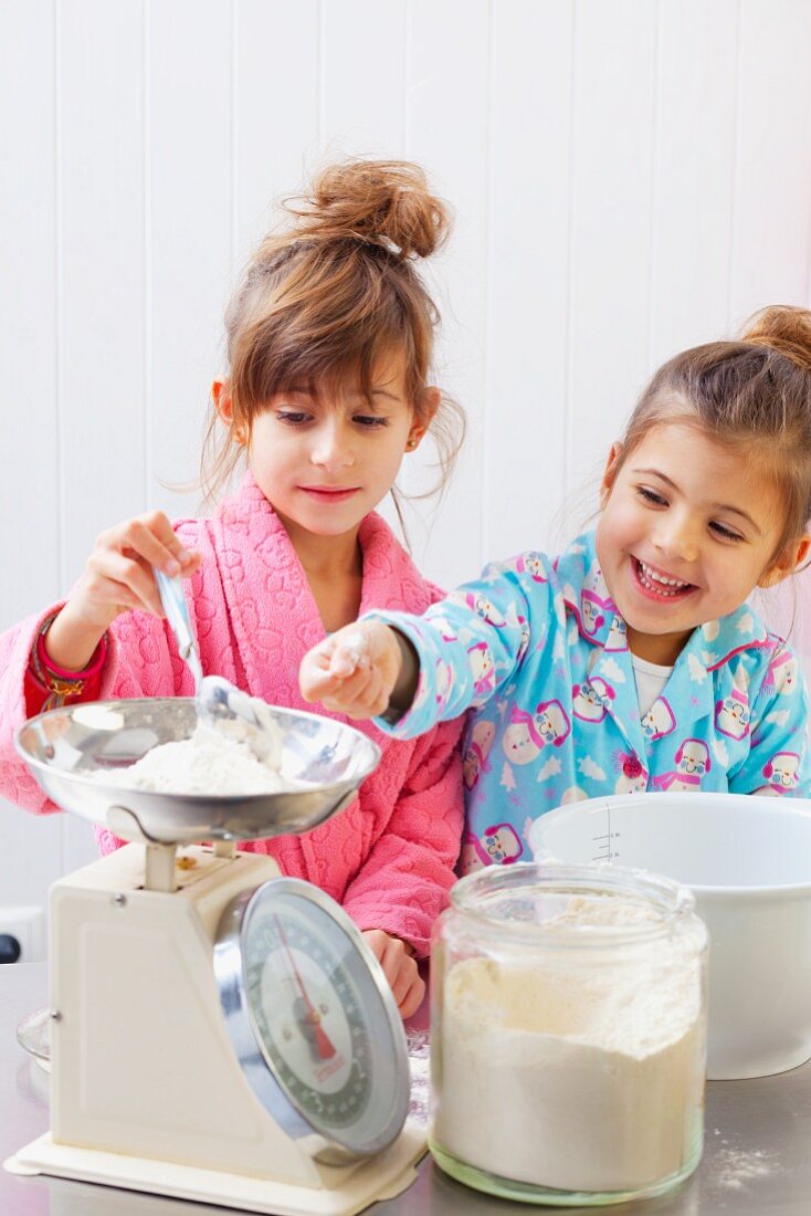 Zwei Mädchen wiegen Mehl auf einer Küchenwaage