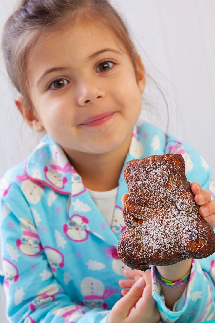 A girl holding up a bear-shaped carrot cake